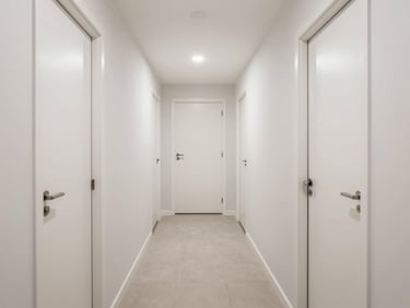 Symmetrical view down a bright residential corridor, flush solid core doors, crisp architectural lighting.