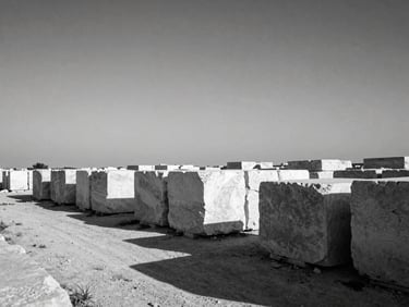 Stark documentary photo of raw limestone blocks stacked in an open field under a harsh Mediterranean sky, deep shadows.