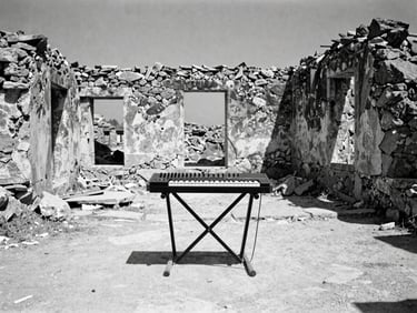 Stark documentary photography of a modern synthesizer setup placed inside a decaying stone ruin, wide-angle cinematic lens, harsh Mediterranean light, 35mm film grain