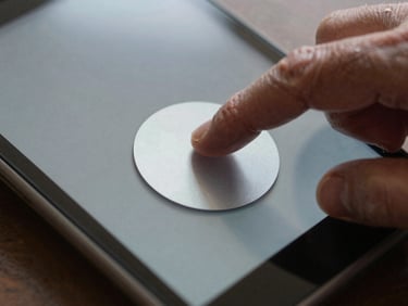 Extreme close-up of a senior's hand tapping a large, high-contrast button on an Android screen, soft silver reflections