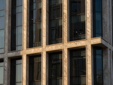 Close-up architectural detail of a modern glass and steel office facade in Riyadh, geometric shadows, warm evening light.