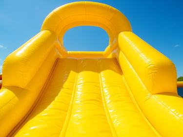 Close-up bright outdoor shot of a clean, sparkling yellow inflatable slide, sun shining on the vinyl surface, showcasing spotless hygiene.