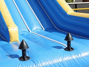 Close-up of safety anchors and soft protective walls on a vibrant blue inflatable, bright daylight.