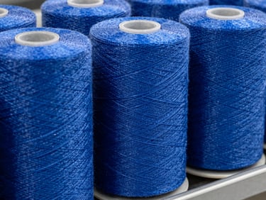 Industrial blue polypropylene tape yarn spools on a manufacturing rack, high-contrast industrial lighting, macro detail