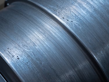 Close-up of hand-patinated steel surface showing deep blue and grey acid wash textures.