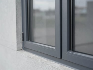 Detail shot of a sleek, modern aluminum window frame against a minimalist concrete wall, cool daylight, 35mm