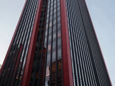 Wide panoramic shot of modern corporate skyscraper facade in São Paulo, sharp angles, clean daylight with subtle crimson reflections