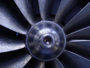 Sharp macro photography of a machined metal aerospace turbine seal face, crisp technical studio lighting, high-contrast metallic textures, deep navy tones, 50mm.