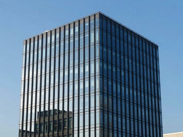 Sleek commercial office building facade, reflective glass, deep blue sky, sharp focus.