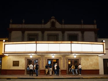 Exterior of a Mexican theater venue at night, warm marquee lights glowing against dark sky, crowd entering through illuminated doors