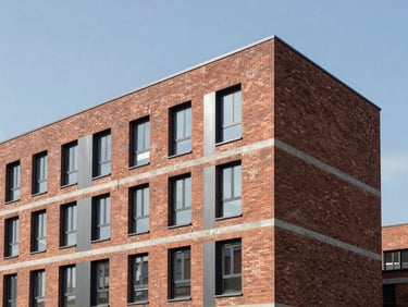 Finished facade of a modern brick and steel residential-over-retail development, clean geometric lines, clear sky.