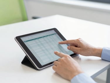 Hands working on a tablet with financial data, bright office, minimal clutter, natural daylight.