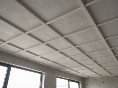 Wide overhead shot of a completed gypsum ceiling grid installation inside a commercial room, natural light entering from side windows, framing channels and joint lines clearly visible