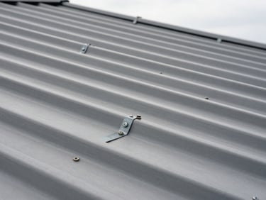 Close-up of roof tile fasteners and metal seam joints on a completed corrugated metal roof, natural overcast daylight, sharp material texture visible