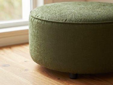 Warm editorial photography close-up of a 360-swivel fabric counter stool in a forest green hue, showing the swivel mechanism and textured fabric, morning light, shallow depth of field