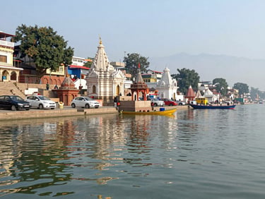 Bright daylight photo of the Ganga Aarti ghats in Haridwar, clean water reflecting temple lights, serene atmosphere.