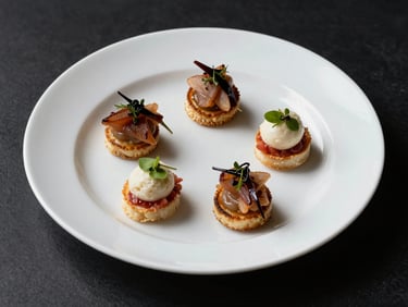 Close-up overhead of a plated corporate gala first course — a precisely composed amuse-bouche on a white porcelain plate, matte black table surface beneath, high-contrast directional studio light, food is the brightest element, no hands visible