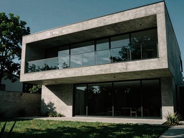 Dramatic low-angle architectural shot of a modern concrete and glass residence, sharp shadows, emerald green landscape accents, medium format film.