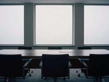 Minimalist wide environmental shot of an empty architectural conference room, soft natural overcast daylight filtering through large windows, muted slate tones, 35mm film.