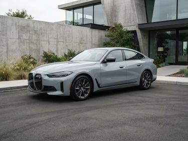 Clean automotive photography, soft overcast daylight. A three-quarters exterior view of a meticulously detailed gray sedan parked outside a modern minimalist concrete building, sharp focus, 35mm lens.