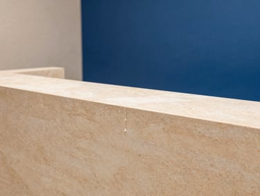 Warm editorial photography of a luxury spa reception, soft beige stone textures, pristine water droplets on clean surfaces, 35mm