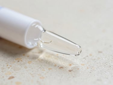 Close-up detail shot of a pristine glass vial reflecting soft daylight on a warm travertine surface, shallow depth of field, 35mm