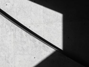 High-contrast black and white photography, sharp geometric shadows on a concrete wall, minimalist architectural line, 35mm lens