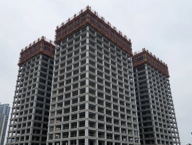 Wide-angle architectural photograph of a modern commercial building under construction in a dense urban environment, steel skeleton visible, crisp overcast daylight, high-contrast cool tones, sharp focus, 35mm