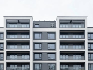 Architectural shot of a contemporary multi-family residential building facade, clean lines, crisp overcast daylight, high-contrast cool tones, 35mm.