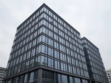Wide-angle architectural shot of a modern commercial office building under construction, glass and steel facade, crisp overcast daylight, high-contrast cool tones, 35mm.