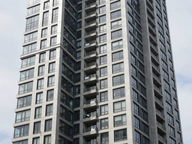 Exterior view of a newly completed high-rise multi-family residential building in Jersey City, modern architecture, hard daylight, high-contrast cool tones, sharp focus, 35mm