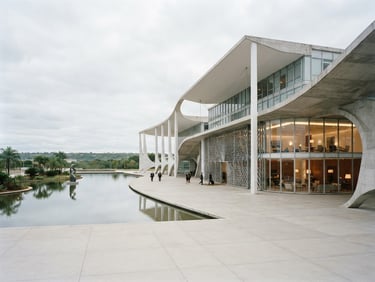 Wide cinematic architectural shot of a modern Brazilian civic palace, concrete and glass curves, soft overcast daylight, clean lines, negative space on the left
