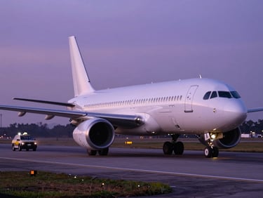 Wide cinematic shot of a commercial airliner taxiing at dusk, dramatic purple runway lights reflecting on the fuselage.