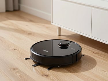 Sleek black robotic vacuum cleaner on a light hardwood floor, cleaning near a minimalist white cabinet, soft daylight