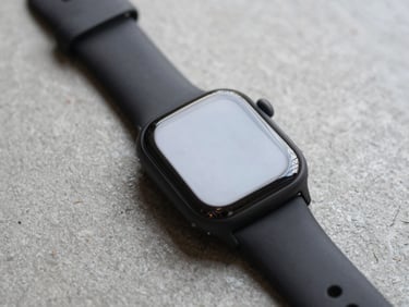 Minimalist smartwatch with black band on a clean concrete surface, soft overhead light, focus on the screen