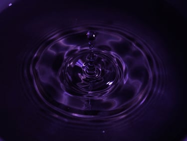 Macro photography of water ripples expanding outwards on a dark cosmic liquid surface, high-contrast chiaroscuro, deep violet tones, 35mm lens