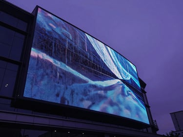 Low-angle heroic wide shot of a massive curved digital screen on a sleek modern building facade at twilight, deep violet ambient light, cinematic 35mm