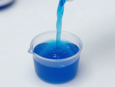 Macro shot of a viscous, vibrant blue detergent liquid pouring smoothly into a measuring cap, clean white laboratory background, bright clinical lighting, sharp focus, 35mm.