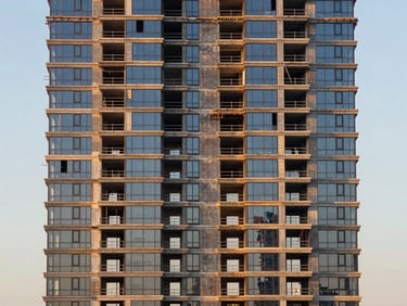 Straight-on facade detail of a Creek Harbour off-plan tower under construction, scaffolding removed from lower floors revealing glass skin, golden-hour light, wide environmental frame