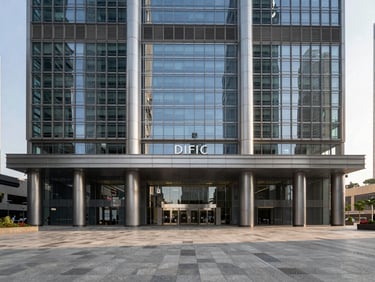 Wide architectural photograph of DIFC's Gate Building facade under sharp afternoon light, glass and steel geometry, empty pedestrian plaza in foreground, financial district context