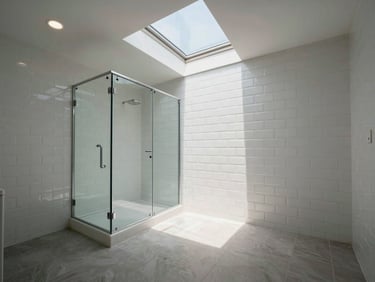 Completed bathroom interior under overhead window light, white subway tile walls, frameless glass shower enclosure visible, natural daylight from above, wide environmental shot of the full room, no people