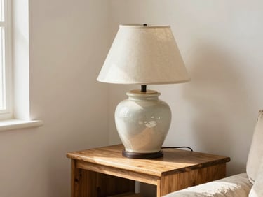 A warm cozy living room corner with a vintage ceramic lamp on a wooden side table, natural daylight