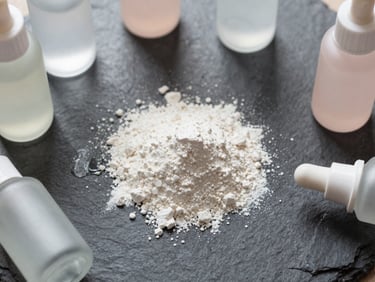 Overhead flatlay of pure niacinamide powder on a wet slate surface, soft diffused light, 85mm