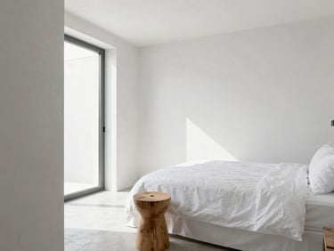 Boutique hotel room interior, bright natural light, concrete textures, natural wood stool, white linen bedding, minimalist design.