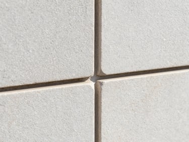 Tight macro shot of interlocking stone joints with a clean polymeric sand seal, high-contrast texture, bright morning sun.