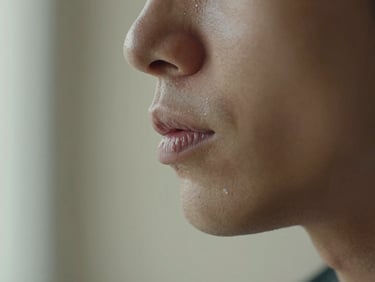 Extreme close-up of a singer's throat and jaw in profile, north window light, concentration visible in the set of the jaw, plain cream wall behind