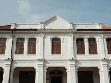 Crisp architectural lines of a heritage venue in Penang, Malaysia, bright daylight, raw natural textures surrounding the colonial facade.