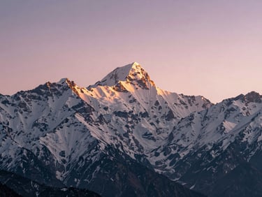 Expansive view of snow-covered Himalayan peaks at sunrise from Pokhara, soft pink and gold light, low horizon