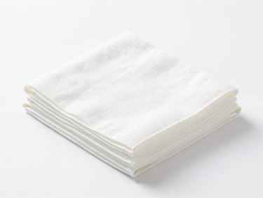 Bright high-key studio shot of folded white paper hand towels, clean white backdrop