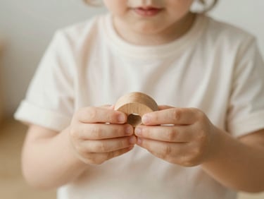 Close-up of a child holding a wooden toy with soft light, warm tones, candid lifestyle photography